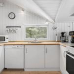 Kitchen with white cabinets, wooden countertops, and window to the forest.