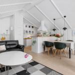 Living and dining area with sofa, dining table, and kitchen under high ceiling.