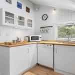 Kitchen with white cabinets, wooden countertops, and view of forest.