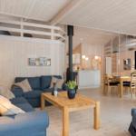 Living and dining area with wooden walls, sofa, dining table, and wood stove.