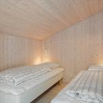 Two single beds in a room with wooden walls and wall lights.
