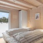 Bedroom with wooden walls and window view of snow and trees.