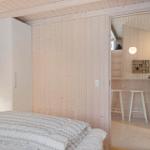 Bedroom with bed and wardrobe. Passage to small bar with stools.