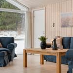 Living room with sofa, coffee table, and fireplace. Large windows show forest and snow.