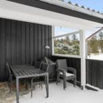 Patio with table, chairs, and grill under roof. Snow covers the ground and surrounding trees.
