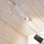 A white ceiling lamp with USB port charges a smartphone.