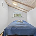 Bedroom with blue quilt and wooden ceiling.