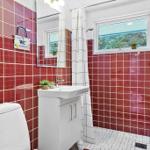 Bathroom with red tiles, sink, toilet, and shower with curtain.