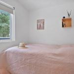 Bedroom with bed, window, and wall shelf.