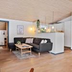 Living room with sofa, table, and hardwood floor. Kitchen and bedroom are visible.