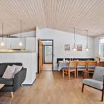 Living and dining area with wooden ceiling, sofa, table and chairs.