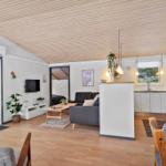 Apartment with open kitchen, sofa and TV. Wooden floor and sloped ceiling.