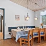 Dining room with wooden table, blue striped tablecloth, and bench. Window with view of forest.