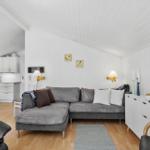 Living and kitchen area with gray sofa, white walls, and wooden floor.