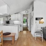 Kitchen with dining area and living area in a bright room with wooden floor and white walls.