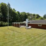House with garden, sun loungers, and terrace under trees.