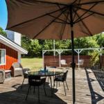 Deck with table, chairs, and umbrella beside red house.