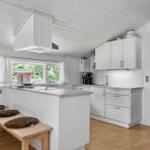 Kitchen with white cabinets and wooden floor. Window with view of garden.