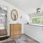 Kitchen with white cabinets and wooden dresser. Hallway leading to garden view.