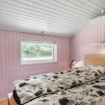 Bedroom with pink paneled walls, bed, and window.