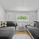 Two sleeping areas with dark bed covers and colorful pillows.