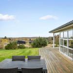Deck with table and chairs, view of green lawn and forest.