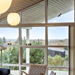 Large window with view of forest and sky. Seating area and ceiling lights visible.