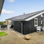 Black wooden house with terrace, garden, and seating areas.