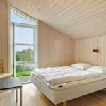 Bedroom with wooden walls and large window to greenery.