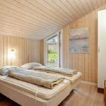 Bedroom with wooden walls, bed, window, and wardrobe.