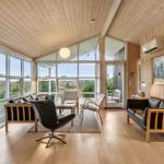 Living room with wooden walls, large windows, and dark sofas.