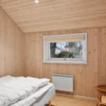 Schlafzimmer mit Holzwand, Bett, Fenster und Heizkörper.