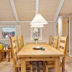 Esszimmer mit Holztisch, Stühlen und Fenster. Decke und Wände sind holzverkleidet.