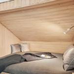 Ein Bett mit Kissen und Decke in einem holzverkleideten Raum mit schräger Decke.