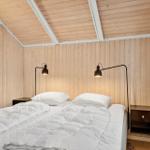 Schlafzimmer mit Holzwand und Bett mit weißen Kissen.