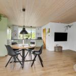 Open space with dining table, kitchen, and TV mounted on the wall.