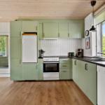 Kitchen with green cabinets, white stove, and black countertop.
