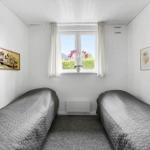 Two beds with gray bedding, window with white curtains and wall decor.