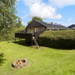 House with terrace, fire pit, and lawn under blue sky.