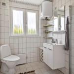 Bathroom with toilet, sink, and shower. Window with view of trees.
