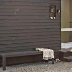 A bench by the door with a cup and cloth on gravel