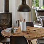 Round wooden table with chairs, coffee mug, and paper towel holder. Background: stove and seating area.