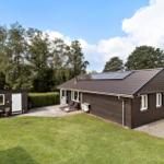 Wooden house with solar panels and garden. Outdoor terrace with sun loungers.