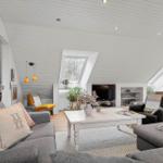 Wohnzimmer mit grauem Sofa, weißem Couchtisch und Dachfenstern.