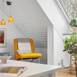 Ein Raum mit gelber Sessel, Pflanzen und Bildern an der Wand.