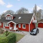 Rotes Holzhaus mit weißem Kranz, Garage und gepflastertem Hof.