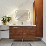 Badezimmer mit Holzschrank, Waschbecken und Spiegel unter schrägem Dach