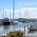 Hafen mit Segelyachten und kleineren Booten im Hintergrund.