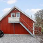 Rotes Holzhaus mit Balkon und Treppe. Auto parkiert auf Kies.