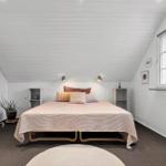 Schlafzimmer mit Bett, Kleiderständer und Fenster